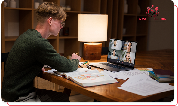 A male student wearing glasses and a green sweater sits at a desk in a cozy room, working in a textbook and taking notes. On his laptop screen, he is participating in a video conference or virtual class session with four other participants visible, illustrating remote or digital education.